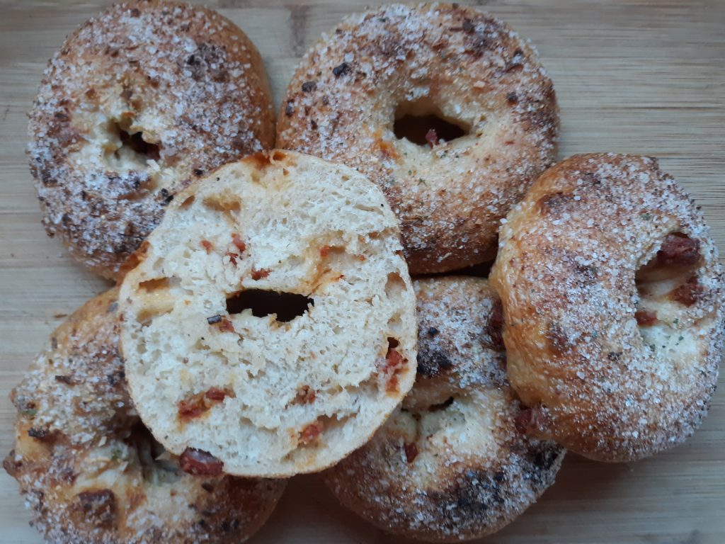 Stack of bagels with a sliced linguica bagel on top.
