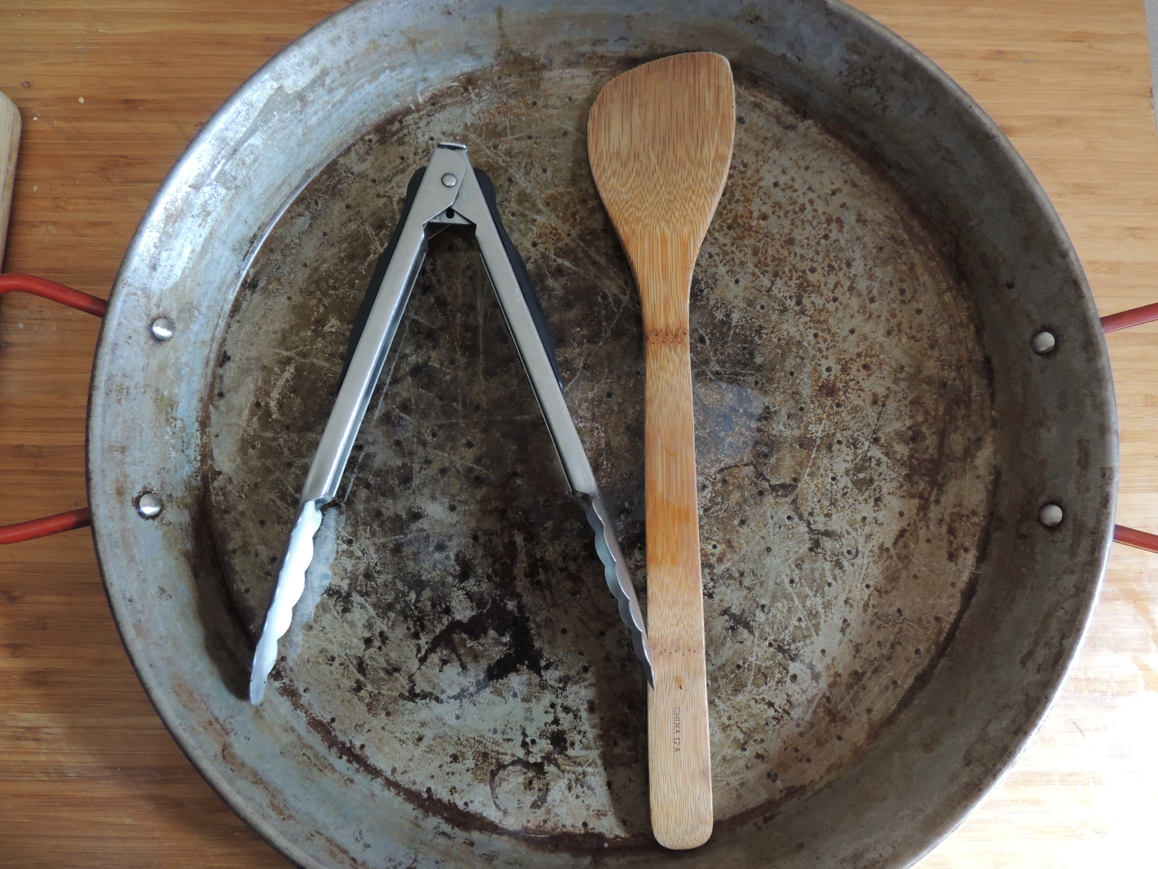Paella pan with tongs and wooden spoon